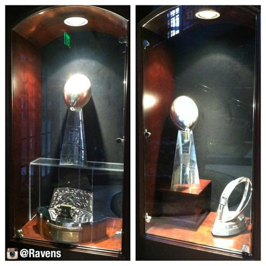 Baltimore's trophy case holding the Super Bowl XXXV & XLVII Trophies along with the AFC Championship units.